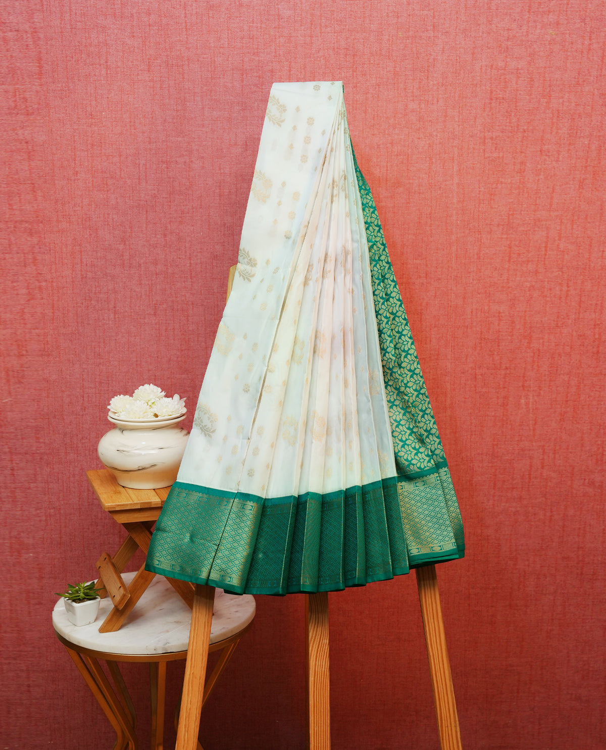 White colour silk saree featuring gold zari motifs on body, contrast teal green with gold zari traditional border, contrast grand pallu comes with matching blouse piece .