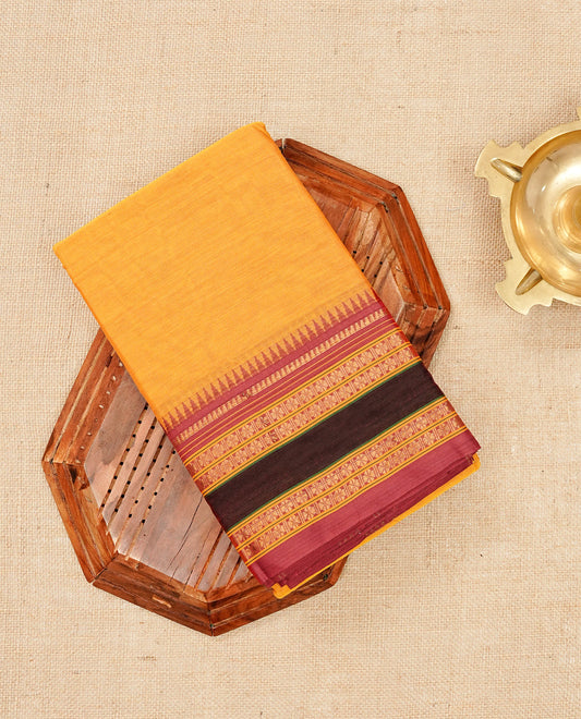 Mustard Yellow colour Narayanapattu cotton saree with a plain body, complemented by a Maroon colour with gold zari border & contrast pallu, paired with a matching blouse piece.