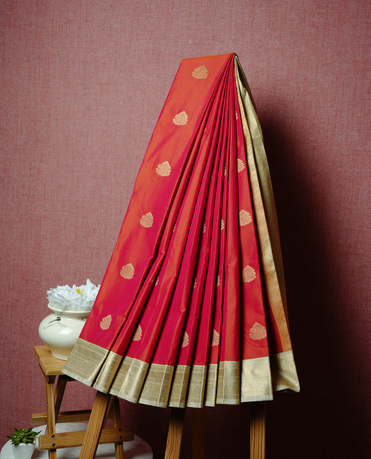 Red coloured soft silk saree featuring gold zari motifs across the body, enhanced with a contrast Cream border and pallu, paired with a matching contrast blouse piece