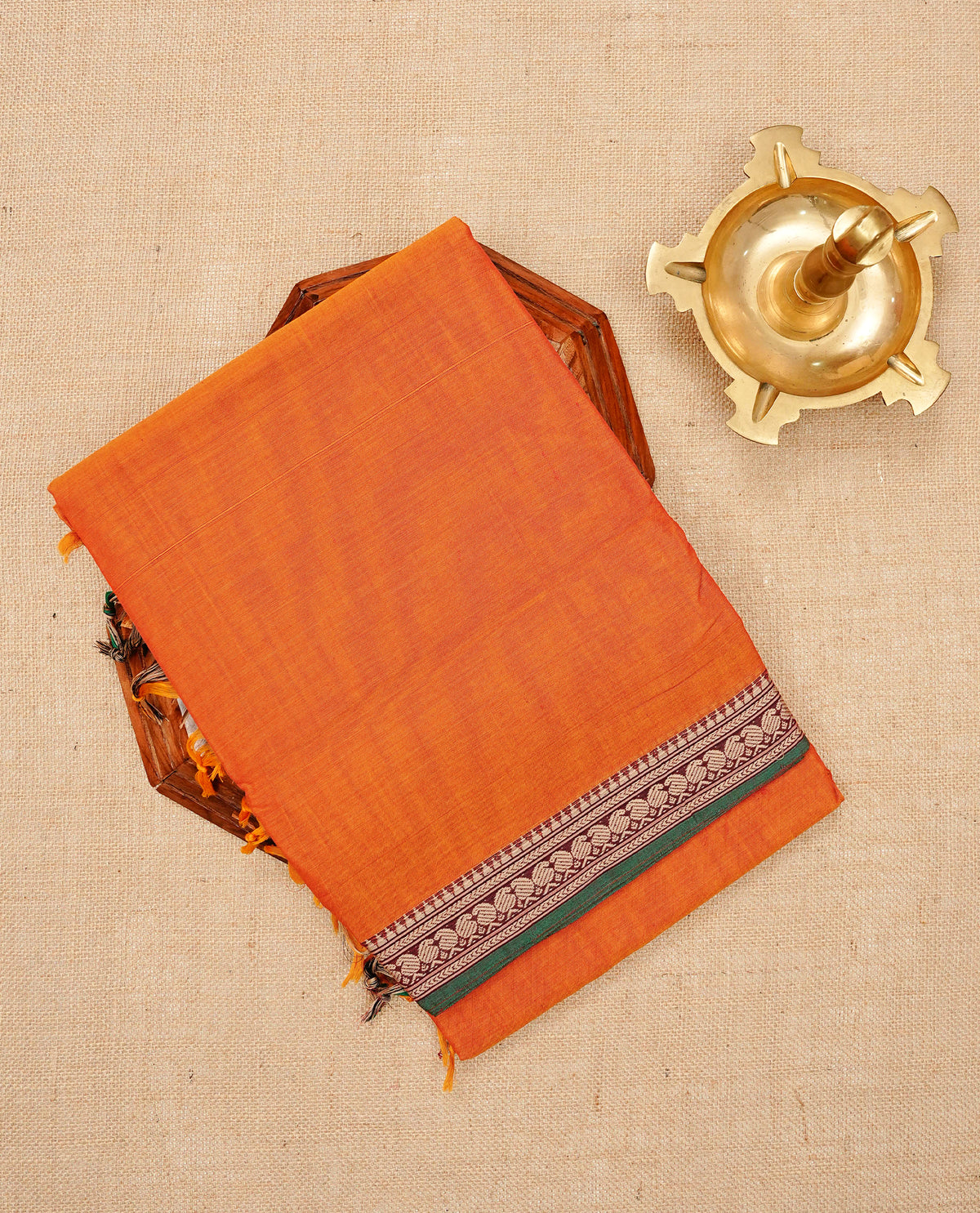 Orange colour Narayanapattu cotton saree with a plain body, complemented by a green colour with Beige colour mango motifs border & a striped contrast pallu, paired with a matching blouse piece.