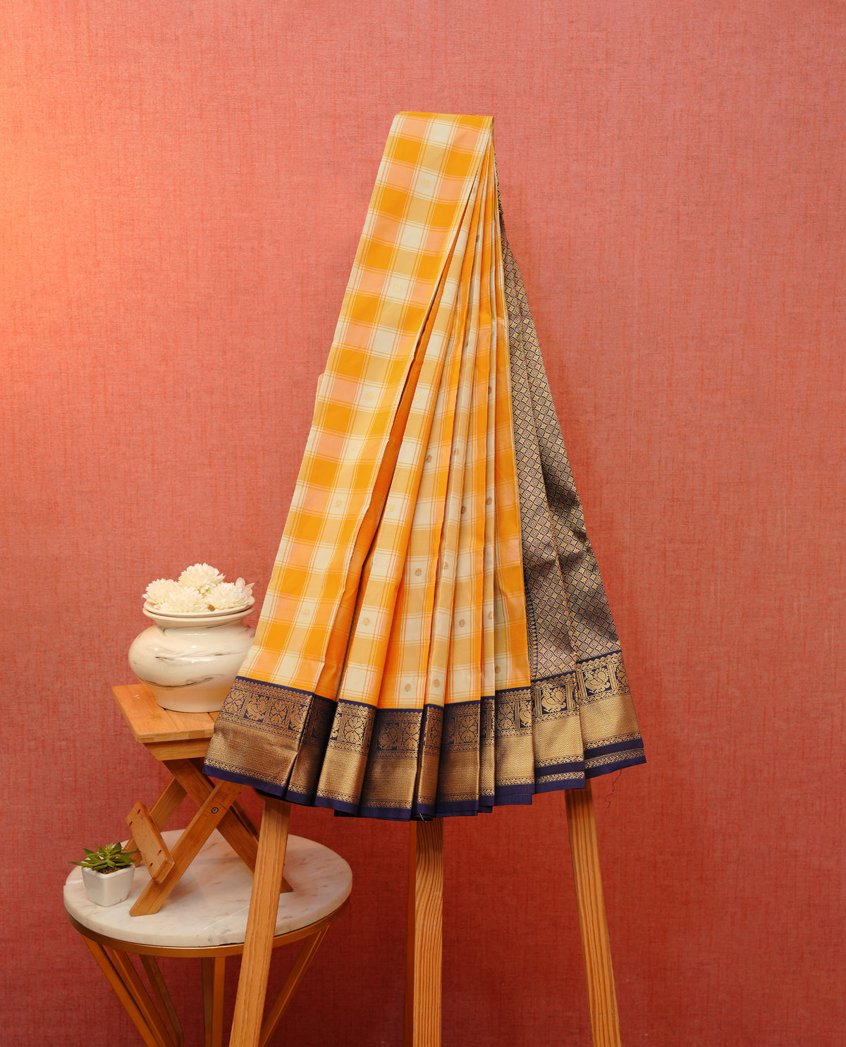 Orange and grey colour soft silk saree featuring gold zari buttas & checks on body, contrast navy blue colour detailed floral & peacock motifs on border, with grand pallu comes with matching blouse piece.