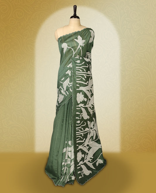 Green colour semi tussar saree adorned with elegant white applique work in leaf and floral designs across the body and border, paired with a matching blouse.