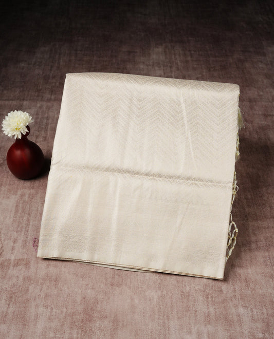 Off white colour softie silk saree featuring silver zari, rich pallu chevron pattern brocade body, with contrasting self colour border.paired with matching blouse piece.