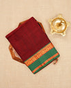 Dark Red colour Narayanapattu cotton saree with a plain body, complemented by a Green Colour with Gold zari border & contrast pallu, paired with a matching blouse piece.