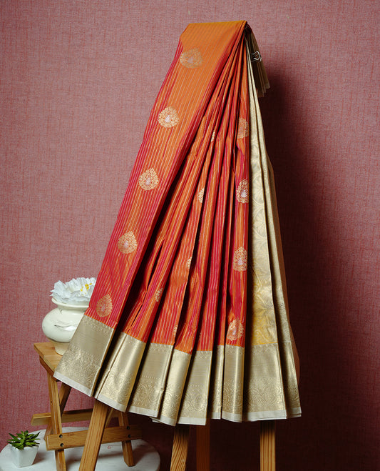 Orange coloured soft silk saree featuring gold zari stripes and motifs across the body, enhanced with a contrast Cream border and pallu, paired with a matching contrast blouse piece.