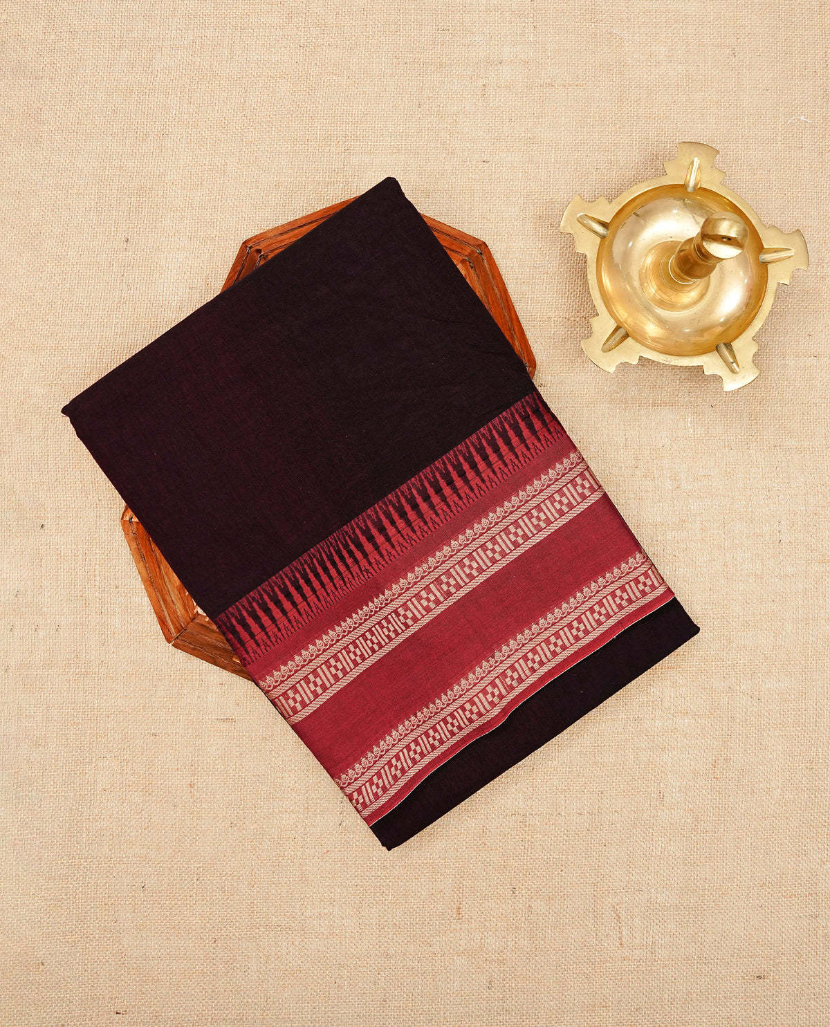 Dark Chocolate Brown colour Narayanapattu cotton saree with a plain body, complemented by a red colour with Beige colour designed border & contrast pallu, paired with a matching blouse piece.