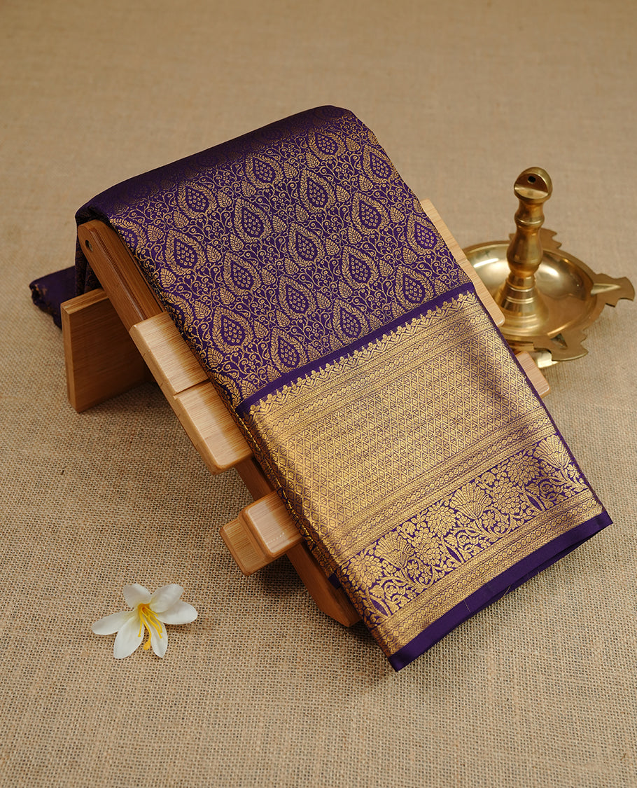 Indigo colour kancheepuram silk saree featuring gold zari floral kodi pattern on body, complemented by self colour with traditional border, paired with matching blouse piece.