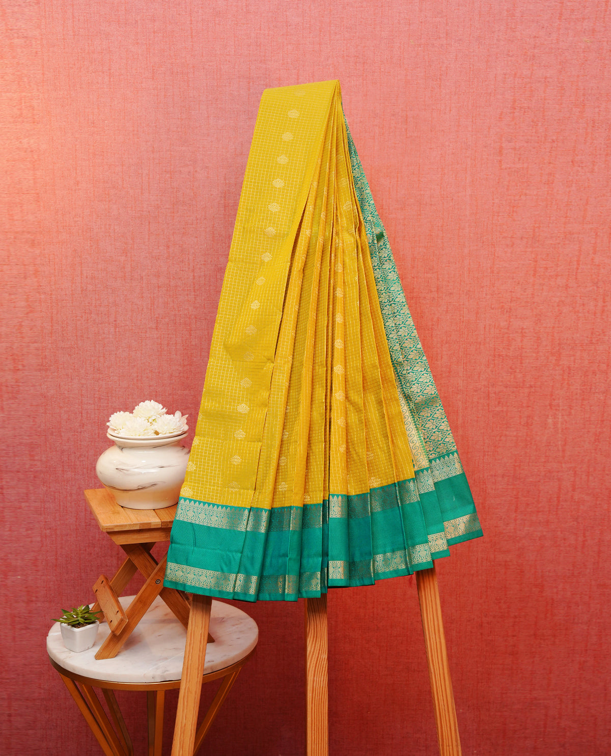 Yellow colour soft silk saree featuring gold zari checks with motifs on body, contrast teal colour traditional border,  grand pallu comes with matching blouse piece.
