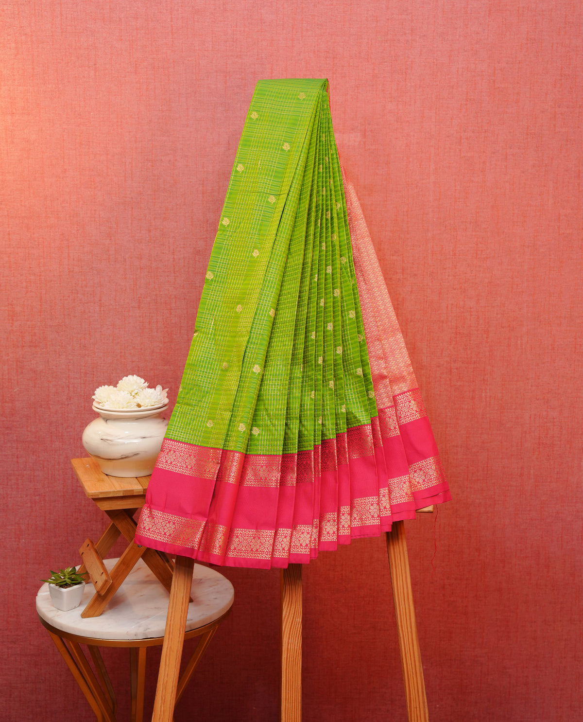 Green colour soft silk saree featuring floral gold zari checks with buttas on body, contrast pink colour traditional border, grand pallu comes with matching blouse piece.