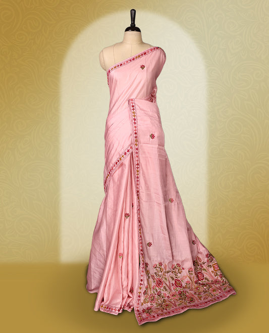 Pink colour pure tussar saree adorned with delicate multicolour floral embroidery along the border and scattered motifs across the body, paired with a matching blouse.