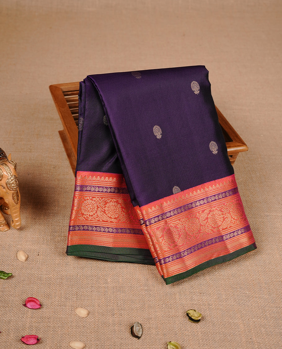 Purple colour traditional kancheepuram silk saree featuring gold zari motifs on body, complemented by contrast orange & green colour with gold zari traditional border, paired with matching blouse piece.