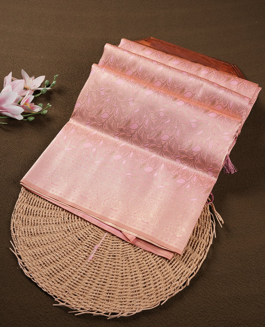 Peach colour semi soft silk saree featuring an all-over woven leaf pattern, finished with a matching pastel peach border adorned with detailed paisley and floral motifs, and a matching blouse piece.