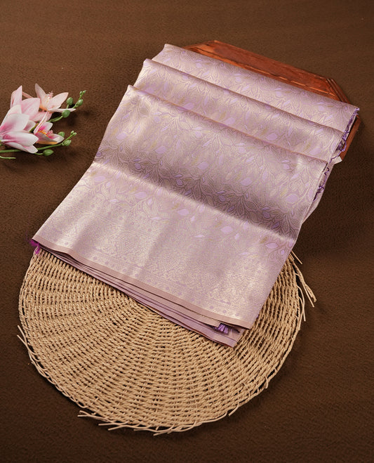 Lavender colour semi soft silk saree featuring an all-over woven leaf pattern in gold colour , finished with a matching border adorned with detailed paisley and floral motifs, and a matching blouse piece.