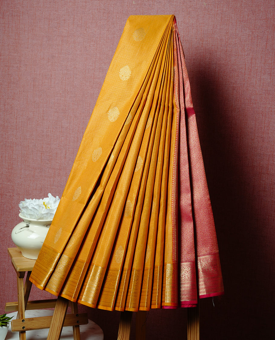 Mustard coloured soft silk saree featuring gold zari stripes and motifs across the body, enhanced with a Self colour border and pallu, paired with a matching contrast blouse piece.