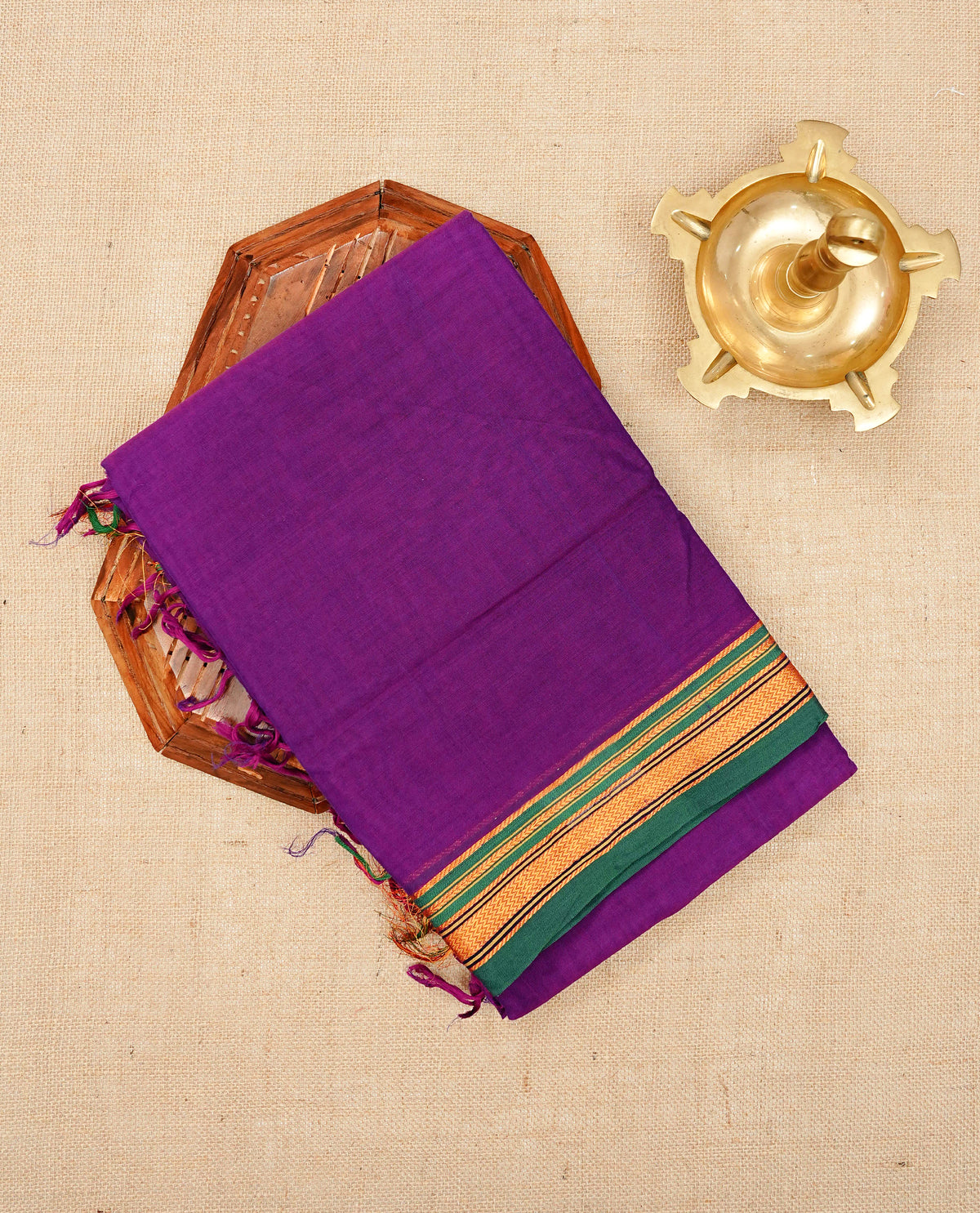 Purple colour Narayanapattu cotton saree with a plain body, complemented by a Green colour with elegant gold zari detailing border & contrast striped pallu, paired with a matching blouse piece.