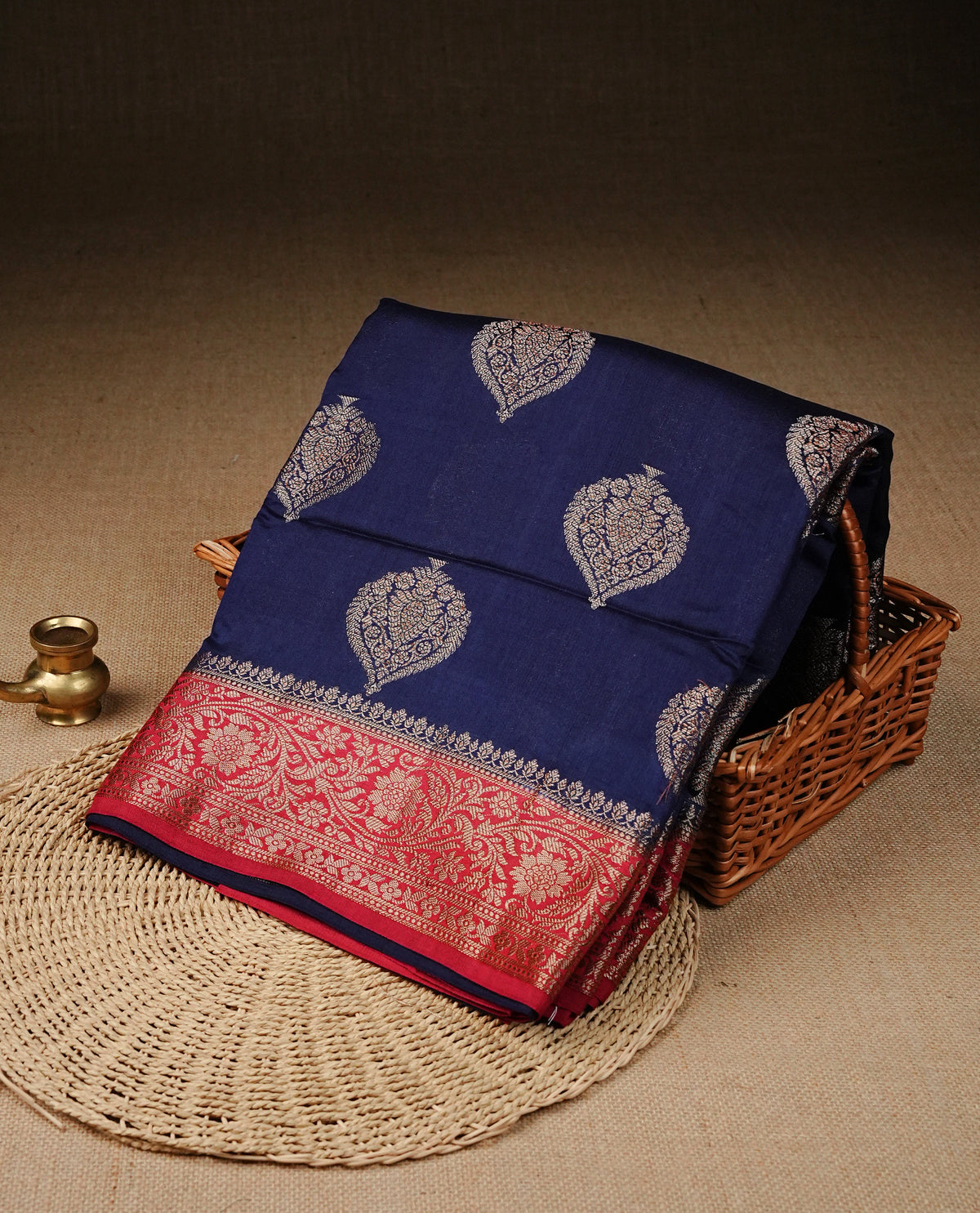 Navy blue colour banaras silk saree featuring gold zari motifs on body, complemented by contrast red colour with traditional border, comes with matching blouse piece.
