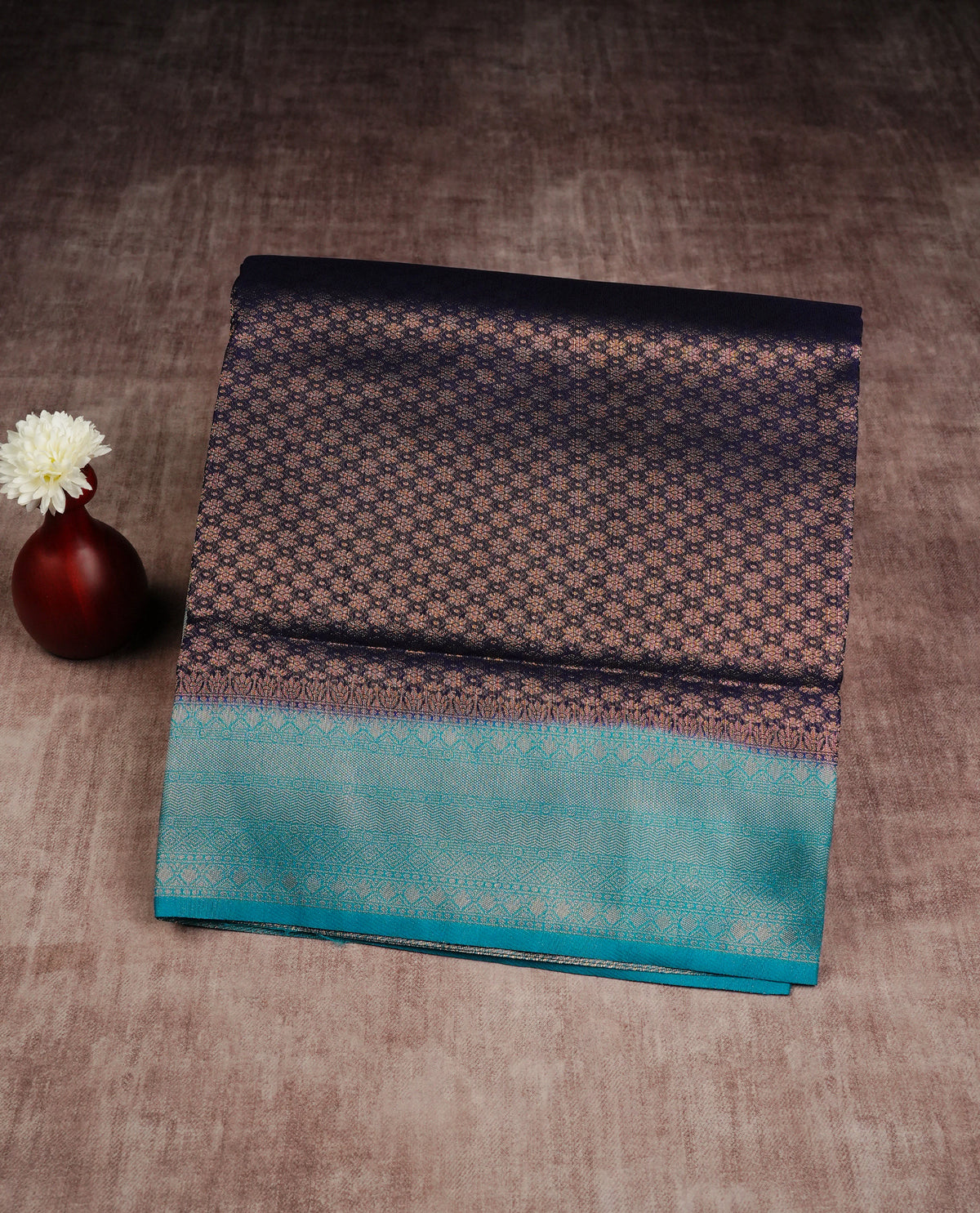 Deep purple colour softie silk saree featuring gold zari, rich pallu floral pattern brocade body, with contrasting teal blue colour border.paired with matching blouse piece.