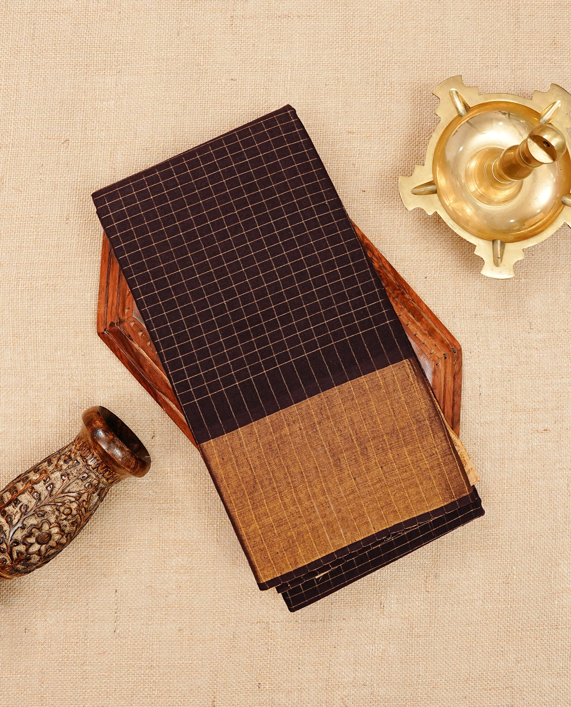 Dark Brown colour Sungudi cotton saree featuring elegant gold zari checks across the body, complemented by a contrast gold zari border. Comes with a matching blouse piece.