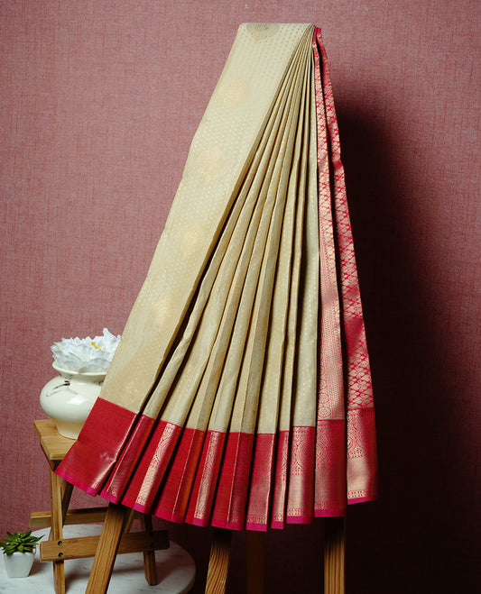 Cream coloured soft silk saree featuring gold zari dotted stripes and motifs across the body, enhanced with a contrast Magenta border and pallu, paired with a matching contrast blouse piece.