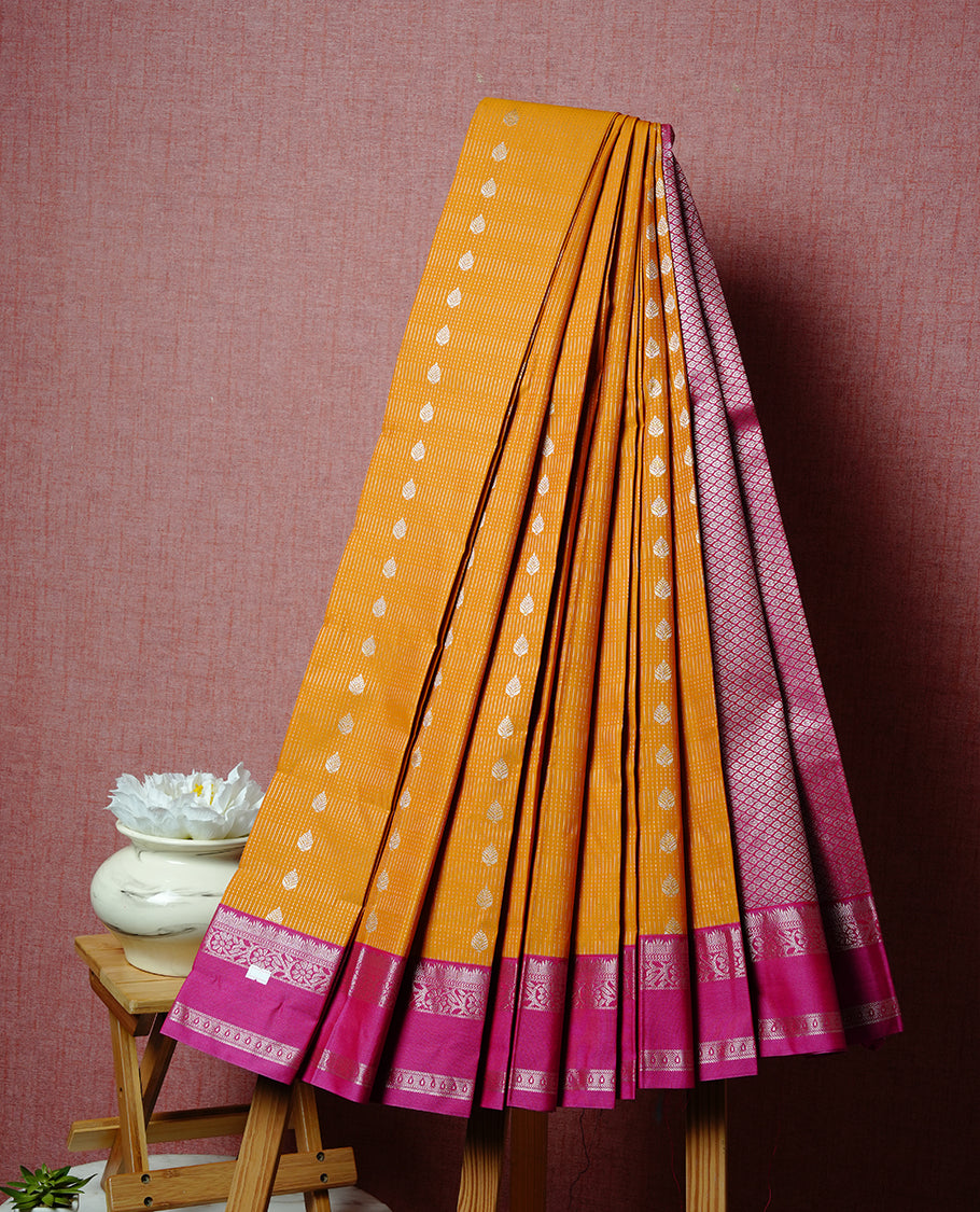 Mustrad coloured soft silk saree featuring silver zari stripes and motifs across the body, enhanced with a contrast Magenta border and pallu, paired with a matching contrast blouse piece.