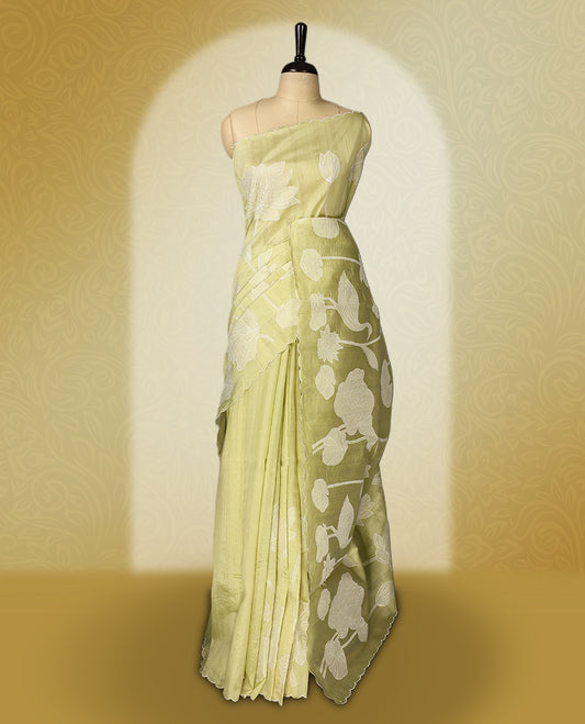 Pastel yellow colour semi tussar saree adorned with elegant white applique work in leaf and floral designs across the body and border, paired with a matching blouse.