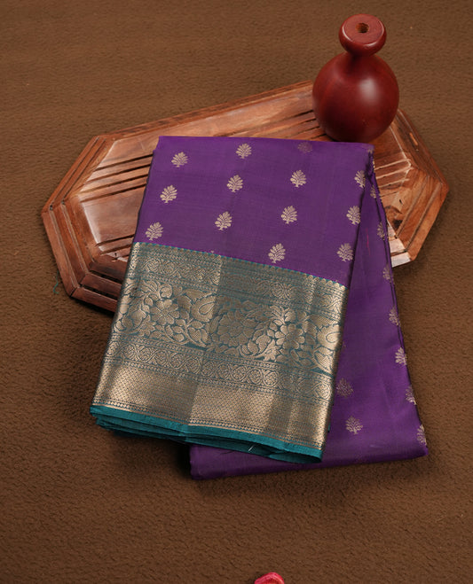 Purple colour soft silk saree featuring gold zari floral motifs on the body, complemented by a contrast green traditional zari floral kodi border and pallu, paired with a matching blouse piece.