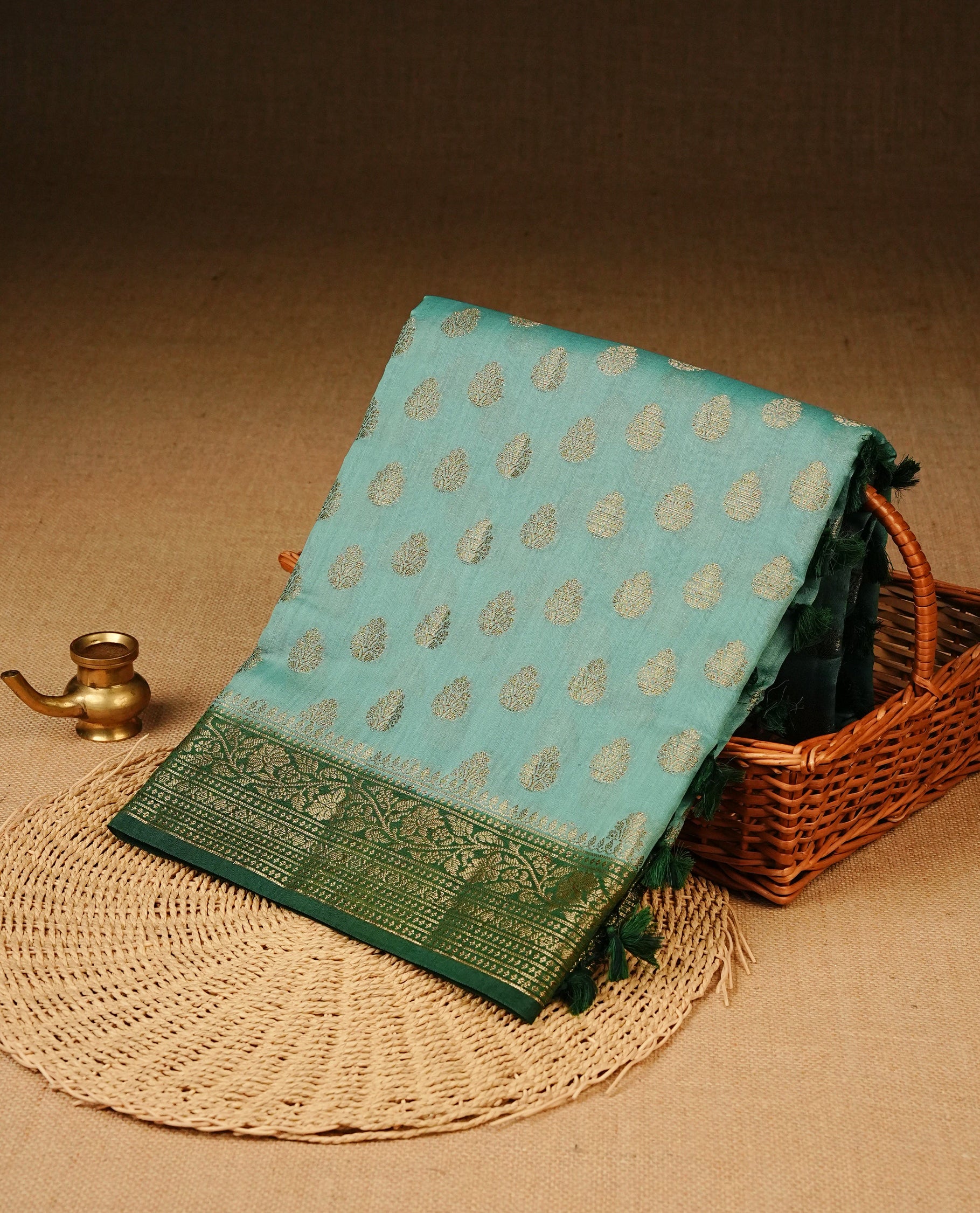 Light Sea Green Colour Tussar Silk saree adorned with antique zari butta motifs across the body, complemented by a contrasting bottle green floral zari border and pallu, paired with a matching blouse piece.