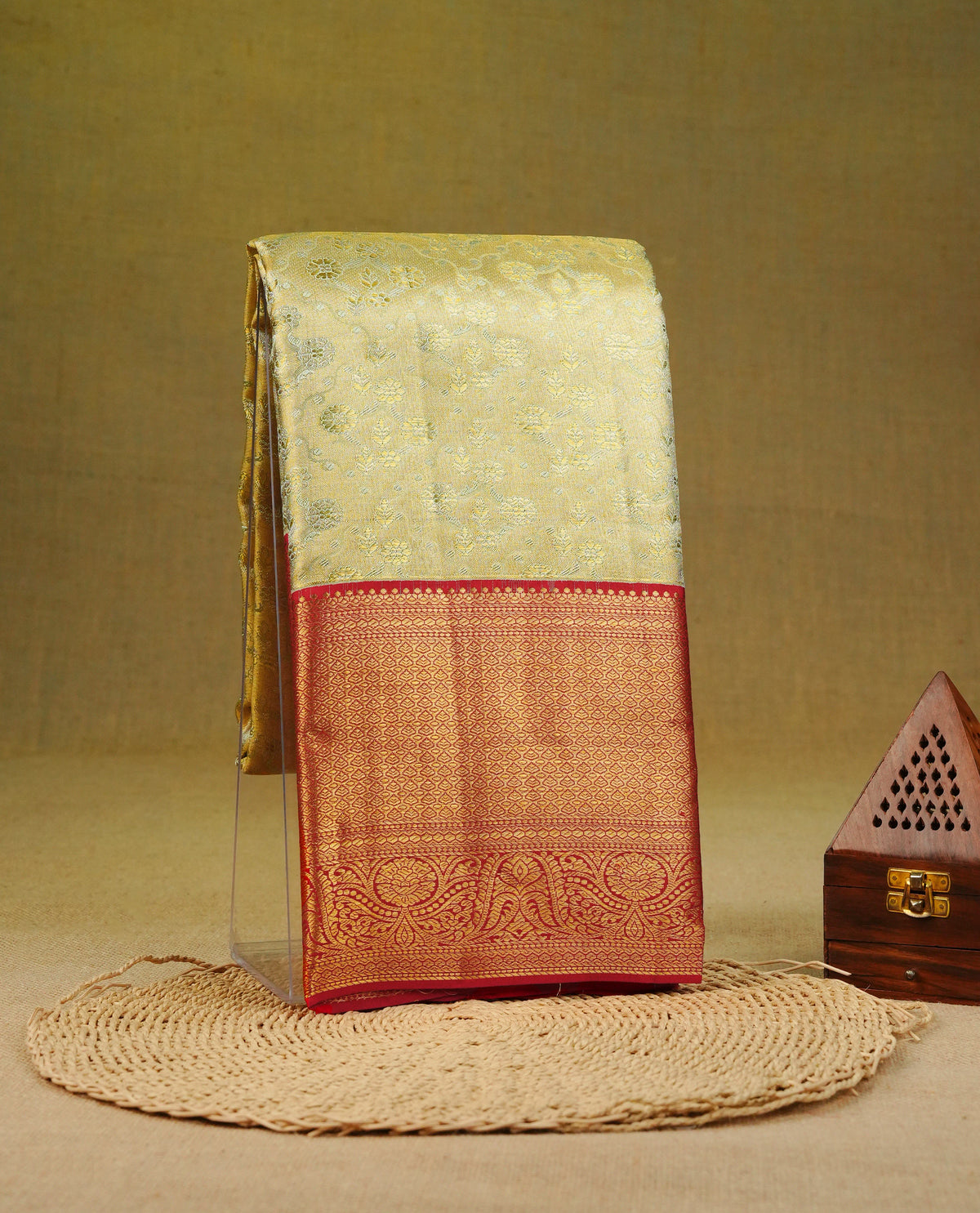 Light gold colour pure tissue silk saree featuring silver zari floral kodi pattern on body, complemented by contrast red colour with traditional border, comes with matching blouse piece.
