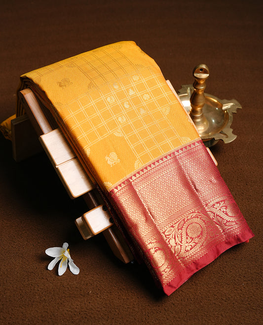 Mustard colour semi wedding saree featuring gold zari motif on check pattern on body, complemented by contrast brick red with traditional border, paired with matching blouse piece.