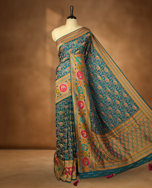 Crystal Teal blue colour Pashmina silk saree densely woven with intricate multicolour floral kodi pattern across the body, framed by an opulent arabesque border and grand storytelling pallu, paired with a matching woven border blouse piece