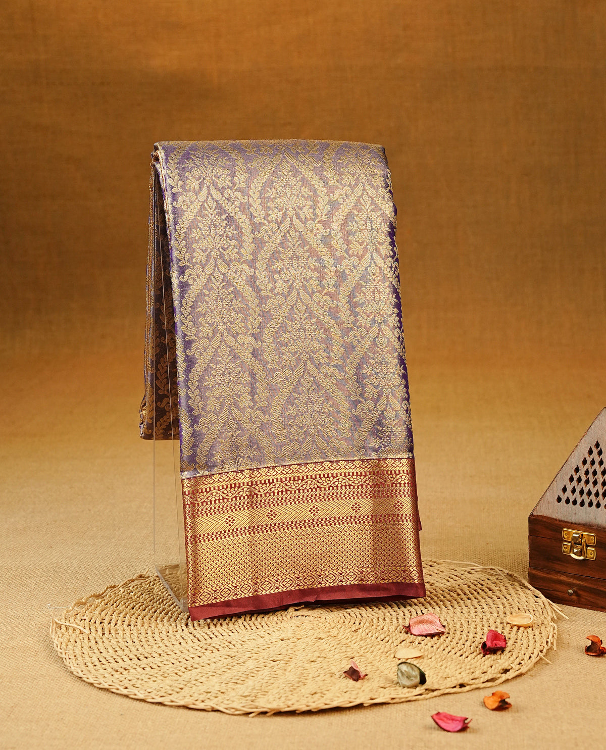Purple colour Semi Tissue Silk Saree featuring gold zari floral kodi Works on the body, complemented by an intricately woven gold zari pallu, a rich Maroon border with gold zari work and paired with a matching plain blouse piece.