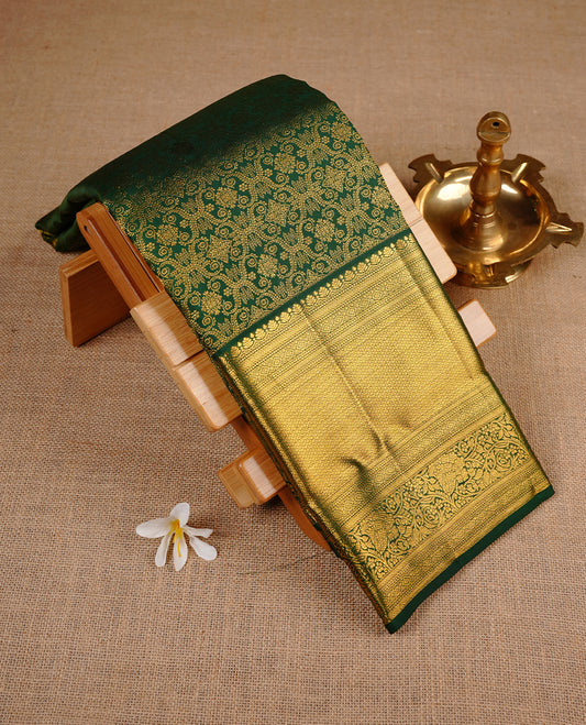 Bottle green colour kancheepuram silk saree featuring gold zari pattern across body, complemented by selfcolour border traditional zari border, paired with matching blouse piece.