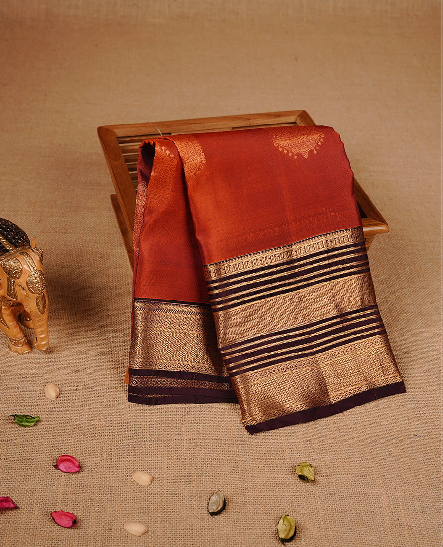 Burnt orange colour traditional kancheepuram silk saree featuring gold zari motifson body, complemented by contrast burgundy colour with gold zari traditional border, paired with matching blouse piece.