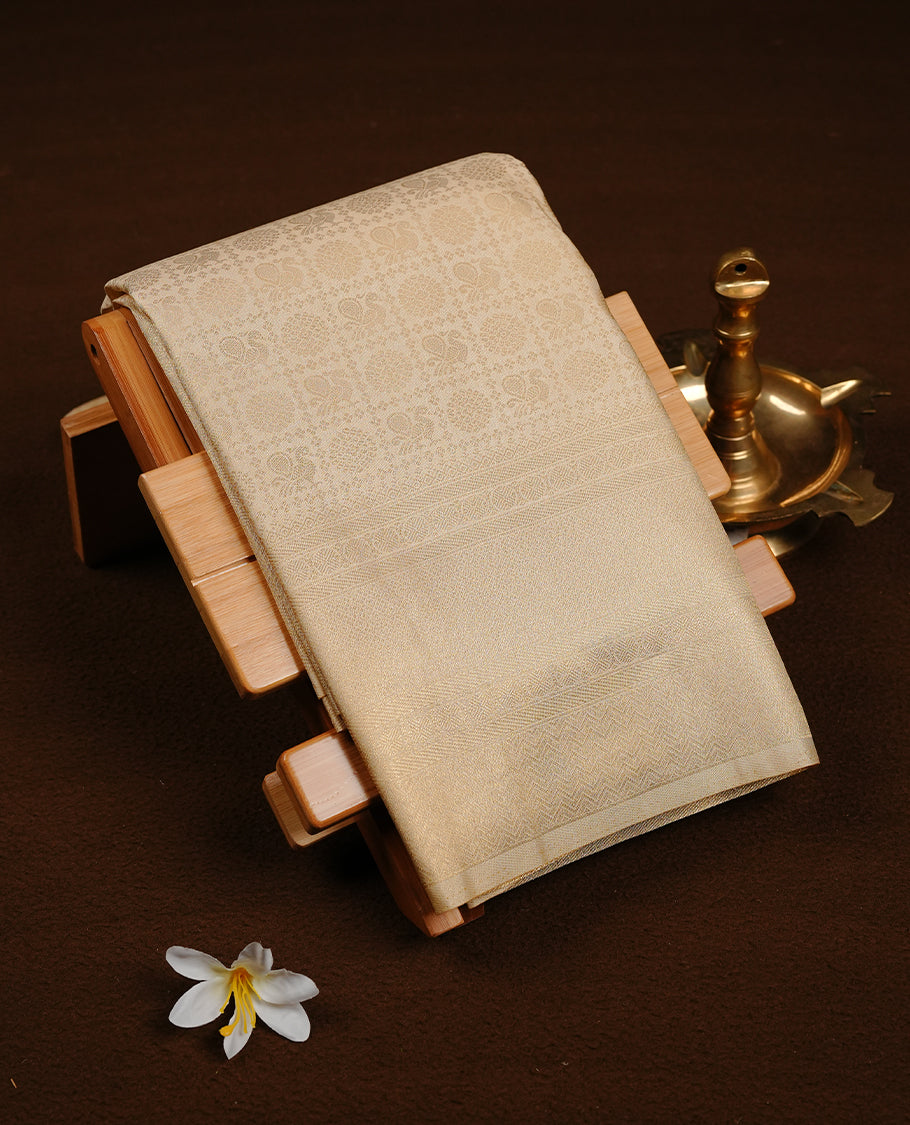 Cream colour soft silk saree featuring gold zari Chakram & peacock motifs inside box pattern on body, complemented by self colour with traditional border, paired with matching blouse piece.