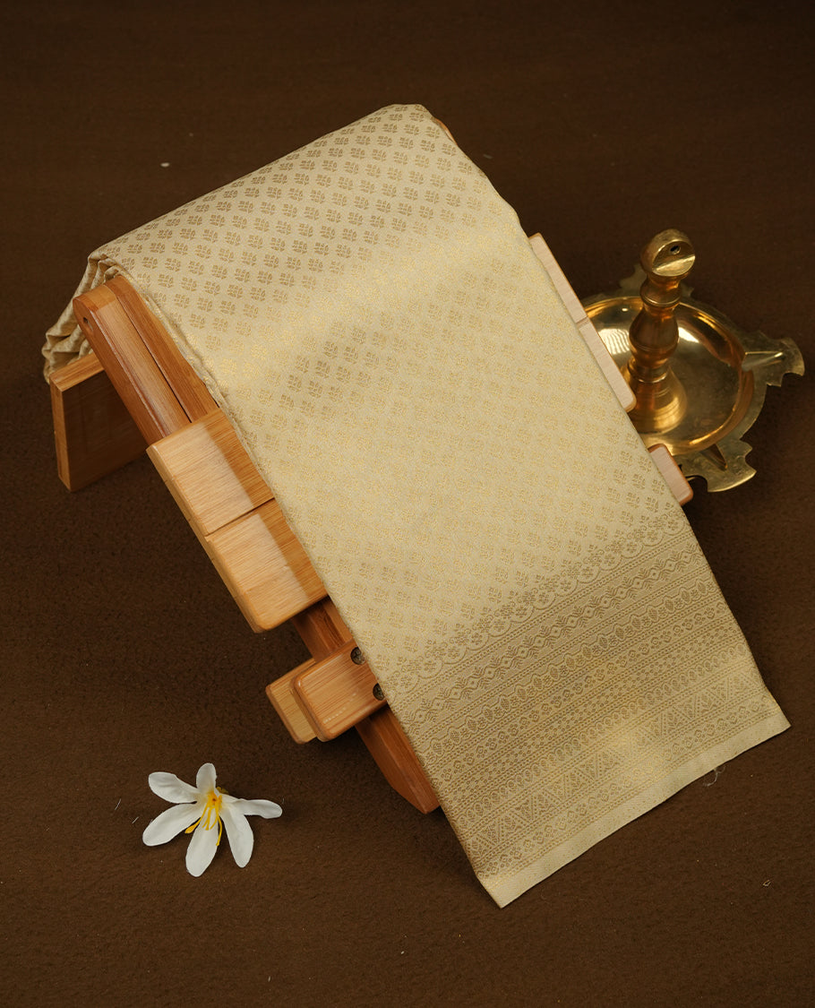 Beige colour semi soft silk saree featuring gold zari motifs on across body, self colour border with traditional gold zari pattern, pallu and paired with matching blouse.