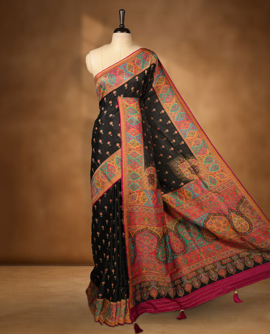 Black colour Pashmina silk saree densely woven with intricate multicolour floral motifs across the body, framed by an opulent arabesque border and grand storytelling pallu, paired with a matching woven border blouse piece