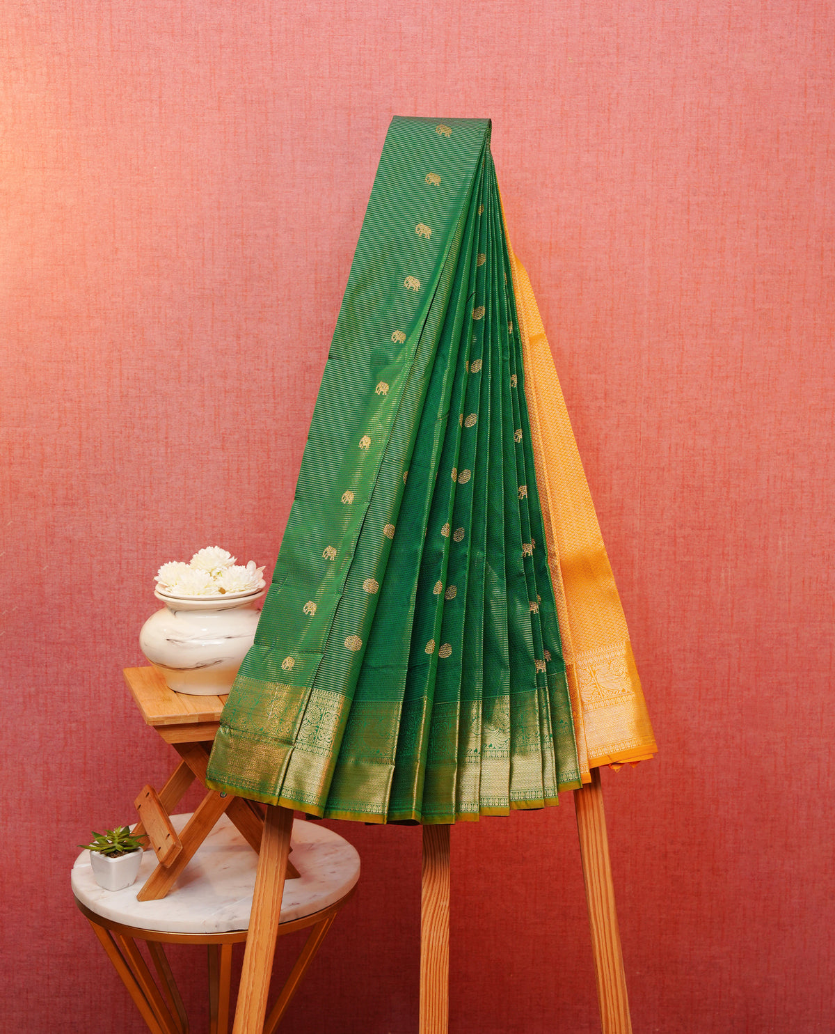 Bottle green colour soft silk saree featuring gold zari lines with elephant motifs on body, contrast Mustard yellow colour gold zari peacock motifs on border, grand pallu comes with matching blouse piece.