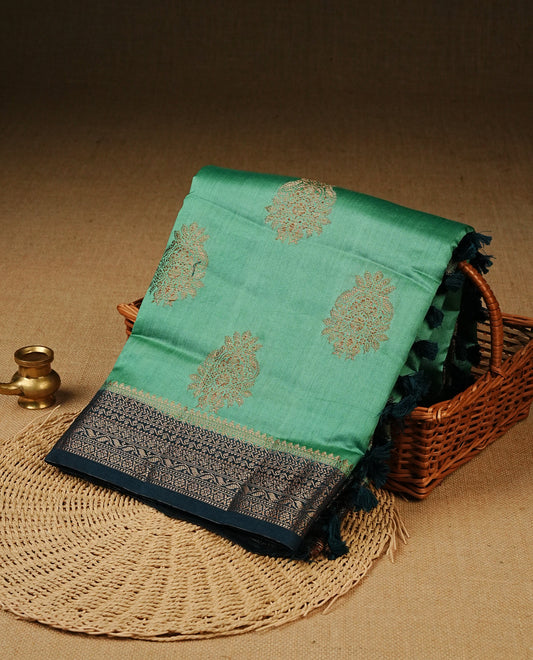 Pastel Aqua Green Colour Tussar Silk saree with elegant antique zari floral motifs On Body, a contrasting Peacock blue zari border, a rich zari pallu, Paired With a matching  blouse piece.