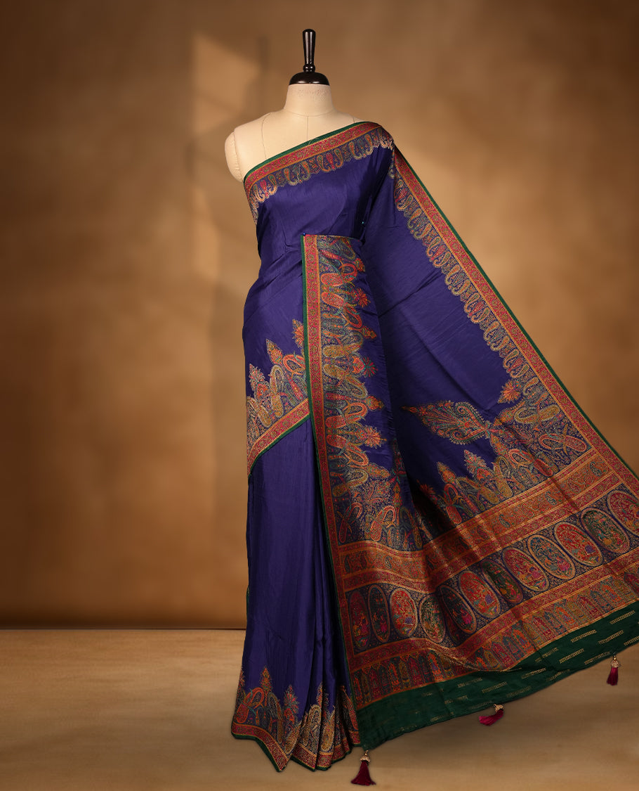 Indigo colour Pashmina silk saree densely woven with intricate multicolour floral and architectural motifs across the body, framed by an opulent arabesque border and grand storytelling pallu, paired with a matching black woven border blouse piece