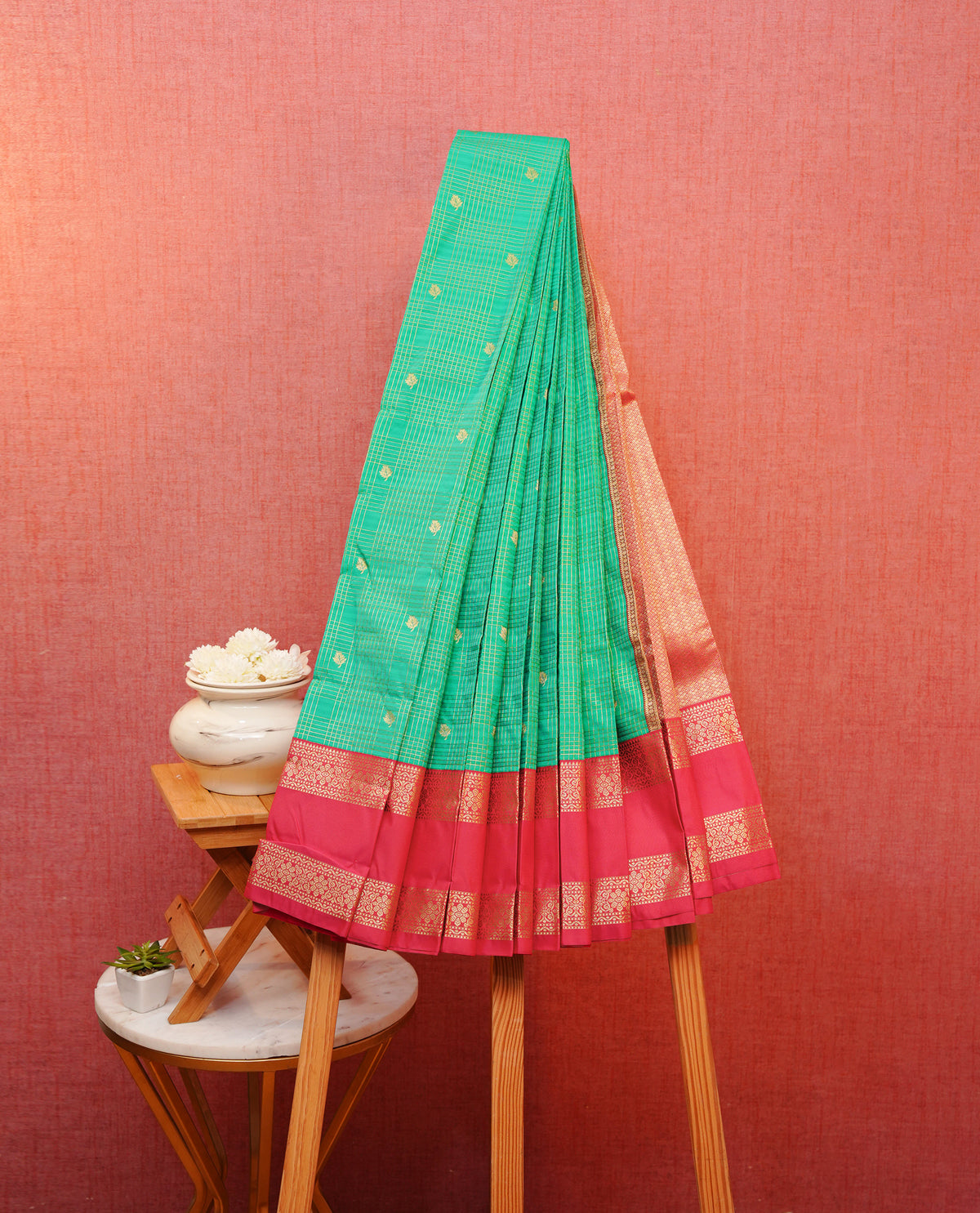 Teal green colour soft silk saree featuring gold zari checks with buttas on body, contrast rani pink colour gold zari floral traditional border, grand pallu comes with matching blouse piece.