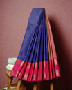 Navy blue coloured soft silk saree featuring gold zari stripes and motifs across the body, enhanced with a contrast Magenta border and pallu, paired with a matching contrast blouse piece.