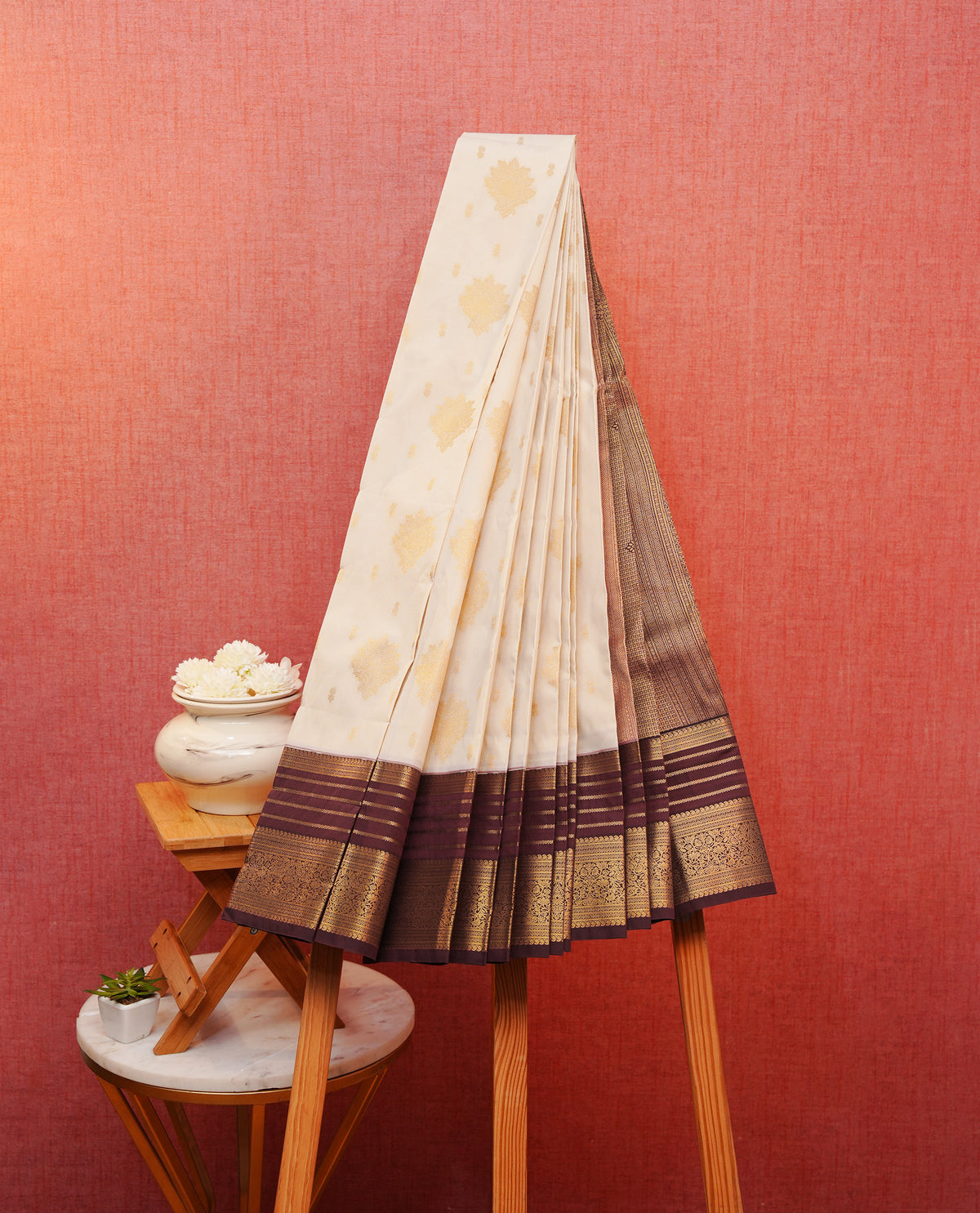 Cream colour soft silk saree featuring gold zari floral motifs & buttas on body, contrast brown colour gold zari traditional border, grand pallu comes with matching blouse piece.