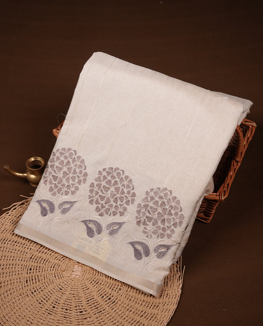 Beige colour Tussar silk saree featuring Elegant plain body, highlighting Grey colour floral cut work with Light gold zari border, pallu and paired with matching blouse piece.