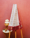 White colour silk saree featuring gold zari motifs on body, contrast red with gold zari traditional border, contrast grand pallu comes with matching blouse piece .