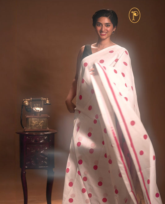 White with Red colour Mul cotton saree featuring polka dot prints across the body, accented with a subtle small border, without a blouse piece.