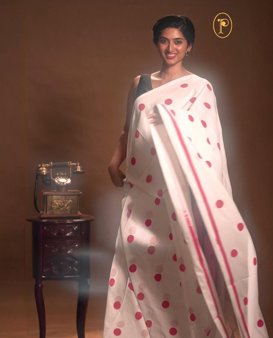 White with Red colour Mul cotton saree featuring polka dot prints across the body, accented with a subtle small border, without a blouse piece.