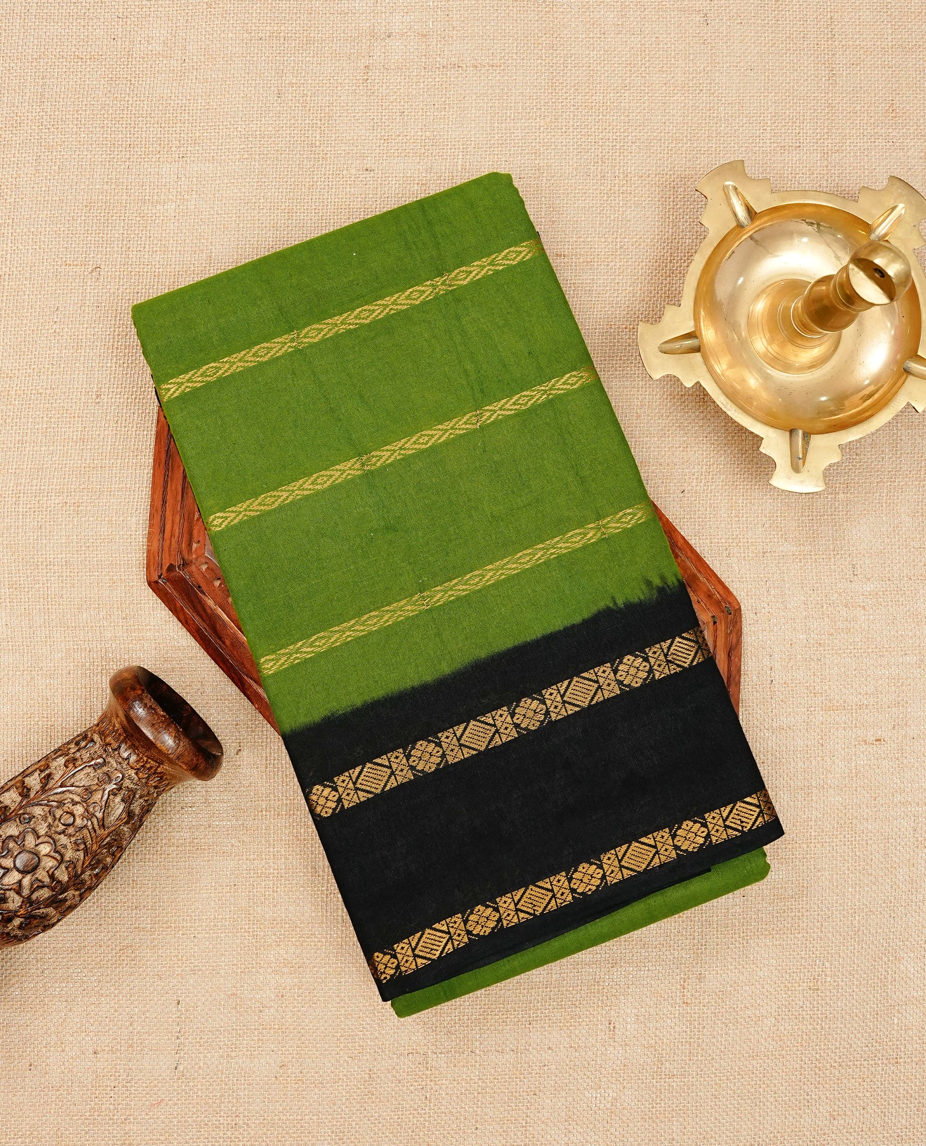 Green Sungudi cotton saree featuring elegant gold zari stripes on the body, complemented by a contrast black with gold zari border and pallu, paired with a matching blouse piece