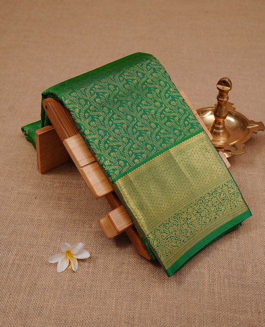 Green colour kancheepuram silk saree featuring gold zari floral kodi pattern on body, complemented by self colour with traditional border, paired with matching blouse piece.