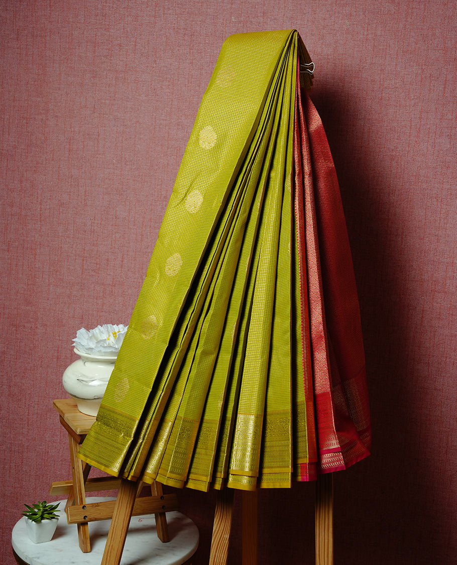 Light oilve coloured soft silk saree featuring gold zari stripes and motifs across the body, enhanced with a selfcolour border and contrast magenta pallu, paired with a matching contrast blouse piece.
