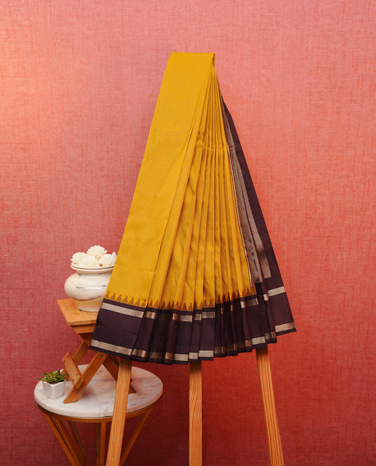 Mustard yellow colour soft silk saree featuring gold zari stripes on body, contrast dark chocolate colour gold zari simple border, grand pallu comes with matching blouse piece.